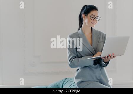 Glückliche weibliche Unternehmer Typen auf Laptop-Computer, arbeitet in modernen Arbeitsbereich im Business-Center, in formellen Outfit gekleidet, surft Internet, Uhren t Stockfoto