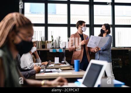 Porträt junger Geschäftsleute mit Gesichtsmasken, die im Büro arbeiten. Stockfoto