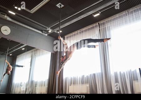 Schöner Mann, der im Studio auf dem Mast tanzt Stockfoto