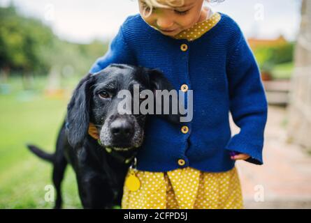 Kleines Mädchen mit Hund im Freien im Garten, zu Fuß. Stockfoto