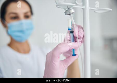 Frau in sterilen Handschuhen, die sich für die intravenöse Therapie vorbereiten Stockfoto