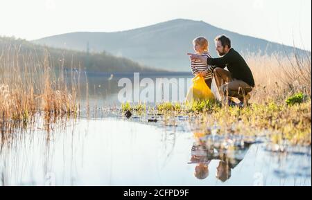 Vater mit kleinen Sohn sammeln Müll im Freien in der Natur, plogging Konzept. Stockfoto