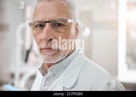 Entschlossener Zahnarzt in Brille posiert in seinem Büro Stockfoto