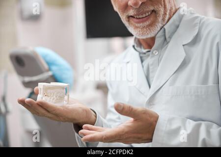 Smiley Zahntechniker hält eine Gipsform der Kiefer Stockfoto