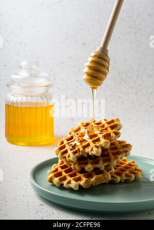 Selektiver Fokus, belgische Zuckerwaffeln mit Blumenhonig auf einem blauen Teller Stockfoto