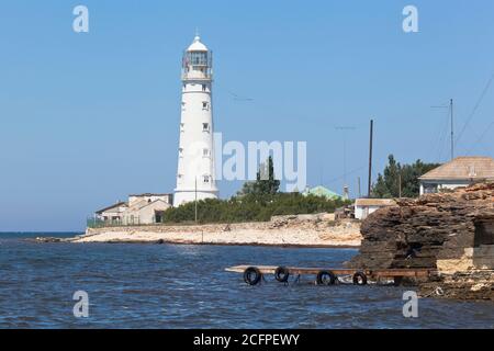 Hölzerne Pier für Ausflugsboote vor dem Hintergrund des Tarkhankut Leuchtturm, Krim, Russland Stockfoto