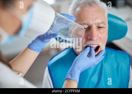 Älterer Bürger, der seinen Mund für eine zahnärztliche Röntgenaufnahme offen hält Stockfoto