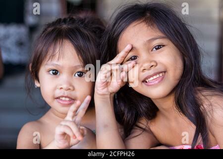 Kota Kinabalu / Malaysia - 13. Januar 2019: Porträt zweier kleiner schöner Mädchen in einem schwimmenden Holzhaus in Kampung Tanjung Aru Lama Stockfoto
