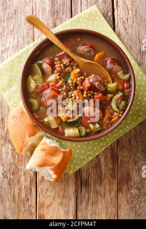 Wurst Linsensuppe mit Tomaten, Zucchini, Karotten, Sellerie und Zwiebeln Nahaufnahme in einem Teller auf dem Tisch. Vertikale Ansicht von oben Stockfoto