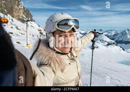 Junge Erwachsene schöne glücklich attraktive kaukasische lächelnde Skifahrer Frau Porträt machen Selfie auf Berggipfel zeigt Skigebiet Panorama Stockfoto