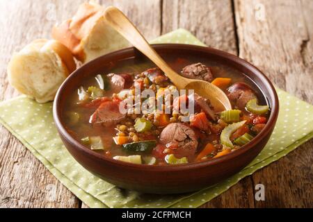 Aromatische gesunde Linsensuppe mit saisonalem Gemüse und geräucherter Wurst in Nahaufnahme auf einem Teller auf dem Tisch. Horizontal Stockfoto