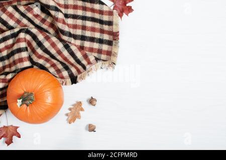 Kürbis, karierten und getrockneten Blättern auf weißem Holzhintergrund Draufsicht. Herbstkomposition. Thanksgiving-Tageskonzept Stockfoto