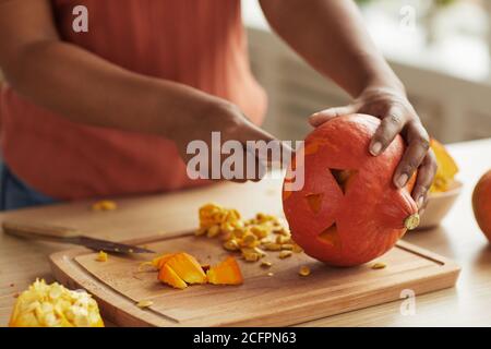 Unkenntlich moderne junge afroamerikanische Frau Schnitzerei kleinen Kürbis für Halloween Dekoration Stockfoto