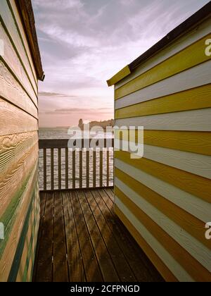 Bunt gestreifte Sommerstrandhütten und Hastings Pier in Hastings Sussex England Großbritannien Stockfoto