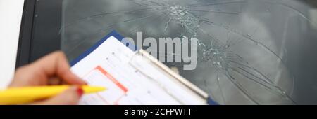 Ein Agent erstellt Dokumente für defekte Windschutzscheibe im Auto. Stockfoto