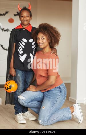 Vertikale voller Schuss der schönen Frau und ihre preteen Sohn Tragen kleine Teufel Kostüm für Halloween Blick auf die Kamera Stockfoto