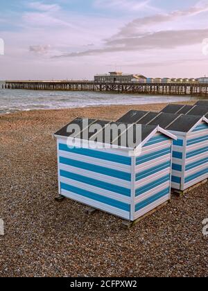 Hastings Beach: Farbenfroh gestreifte Sommerstrandhütten und Hastings Pier in Hastings Sussex England Stockfoto
