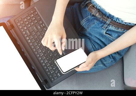 Mockup Bild der Frau Hand hält Handy mit weißem leeren Bildschirm, sitzen mit schwarzem Laptop mit leerem Bildschirm - Online-Shopping, Networking, Stockfoto