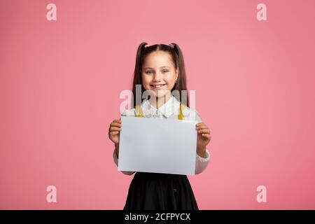 Grundschulbildung. Kleine Schülerin mit glücklichen Lächeln halten Schild mit freiem Platz Stockfoto