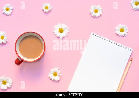 Leeres Notizbuch mit Kaffeetasse, Stift und Blumen auf pastellrosa Hintergrund. Sommer oder Frühling Komposition. Bild mit Kopierplatz, Draufsicht, flach liegend Stockfoto