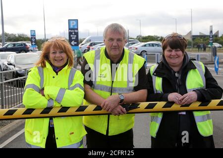 Glasgow Prestwick Airport, Ayrshire, Schottland 05. September 2015, drei Mitarbeiter des Flughafens, die sich an der Parksperrung anlehnen und hohe Visusjacken tragen Stockfoto