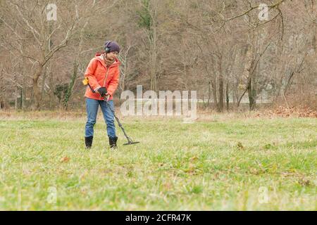 Eine junge Frau sucht mithilfe eines Detektors unter dem Boden nach verschiedenen Metallen. Stockfoto