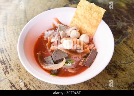 Nudeln mit Meeresfrüchten auf roter Suppe / scharf und würzig thai Essen Nudel Tintenfisch Schweinefleisch Fisch Ball Morgen Ruhm knusprig Wontonhaut Schweinefleisch und Blutwürfel Stockfoto