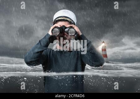 Schiffbrüchiger Steuermann, der mit einem Fernglas den Felsen im Wasser beobachtet Und unter Wasser stehen Stockfoto