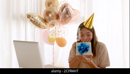 Frau öffnet Geschenk vor dem Geburtstagslaptop Stockfoto