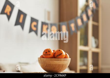 Horizontal keine Menschen Schuss von frischen Mandarinen mit Jack O' Laterne Gesichter auf sie liegend in Holzschale für gezeichnet Halloween-Party Stockfoto