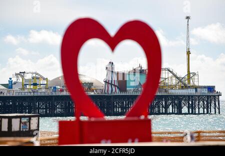 Brighton UK 7. September 2020 - Brighton Palace Pier Helter Skelter wird von einem roten Herzen umrahmt Besucher genießen die warme Herbstsonne an der Küste von Brighton heute als wärmeres Wetter für später in dieser Woche in ganz Großbritannien prognostiziert : Credit Simon Dack / Alamy Live News Stockfoto