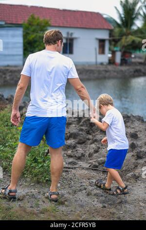 Vater kümmern sich um Sohn, während zu Fuß in der Nähe Bergsee hält führt an der Hand. Frohe Kindheit. Home natürliche Bildung, Vatertag, Papa Stockfoto