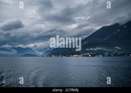 Landschaft des dunklen Comer Sees mit sehr bewölktem Himmel und Bergen, die in Norditalien liegt. Stockfoto