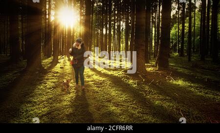 Frau und ihr Hund gehen auf einer Spur im Wald. Wandern, Hundeschule und Outdoor-Aktivitätskonzept. Stockfoto