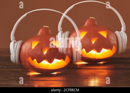 Horizontale Nahaufnahme von Jack O' Lantern Weiße Kopfhörer auf braunem Hintergrund Stockfoto