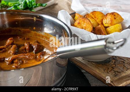 Schweinefleisch Ragout mit cremiger Soße in einem Topf und geröstet Kartoffeln Stockfoto