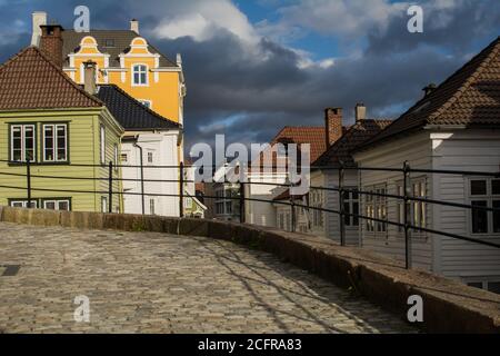 BERGEN, NORWEGEN - 20. Mai 2015: Bergen, Norwegen, 2015. Mai: Altstadt-Straßenszene, oder Gamle Bergen, mit Häusern und dunklen Regenwolken. Stockfoto