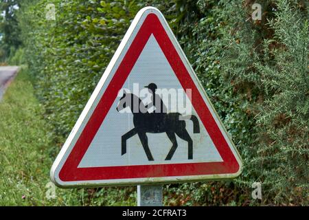 Französisches dreieckiges Metallwarnschild, das ein trabrennendes Pferd darstellt und Fahrer Stockfoto