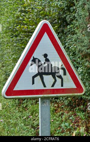 Französisches dreieckiges Metallwarnschild, das ein trabrennendes Pferd darstellt und Fahrer Stockfoto