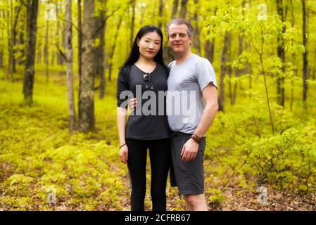 Ein gemischtes rassisches Paar, das an einem sonnigen Frühlingstag in einem Wald in Bushkill Falls Pennsylvania wandert. Stockfoto