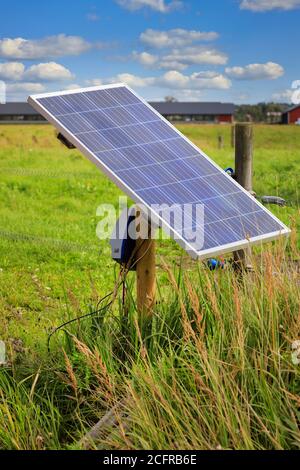 Solarpanel-Ladegerät für elektrischen Zaun auf einem Holzmast montiert liefert die Energie für elektrische Viehzäune auf ländlichen Ackerland in Finnland. Stockfoto