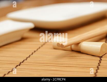 japanische Essstäbchen auf dem Ständer, Bambusmatte und Sushi-Gerichte Stockfoto