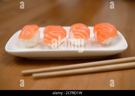 Essstäbchen und Sushi mit Lachs auf der Bambusmatte Stockfoto