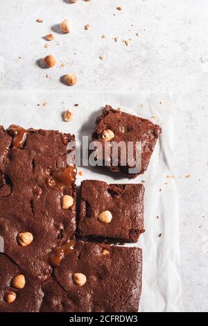 Schokoladen-Brownie mit gerösteter Haselnuss und Karamell mit zwei auf einem Stück Backpapier ausgeschnittenen Stücken. Stockfoto