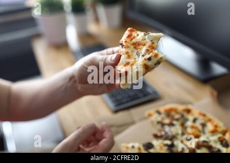 Mann, der Pizza am Arbeitsplatz aus nächster Nähe isst Stockfoto