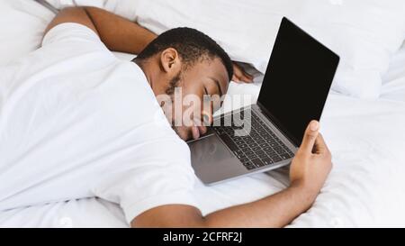 Erschöpft Schwarz Kerl Schlafen Auf Laptop Liegend Im Bett An Zu Hause Stockfoto