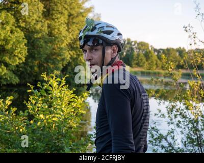 Junger Mann im Fahrradhelm, ernsthafter Blick eines Mannes im Fahrradhelm, Russland, Kaliningrad, 9. Juni 2019 Stockfoto