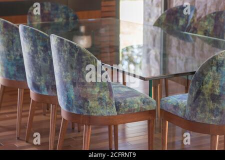 Glastisch und farbenfrohe Stühle im Wohnzimmer, Tageslicht Stockfoto