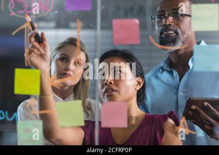 Junge Geschäftsfrau schreiben auf Glasbrett im modernen Büro Stockfoto