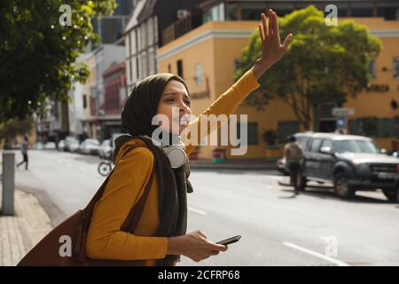 Frau in Hijab, die ein Taxi auf der Straße bejah Stockfoto
